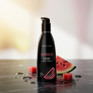Black bottle of Wicked Watermelon flavored water-based lubricant with watermelon slices on a reflective surface.
