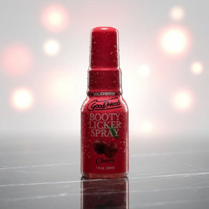 Red bottle of 'Booty Licker Spray' with cherry flavor on a reflective surface.