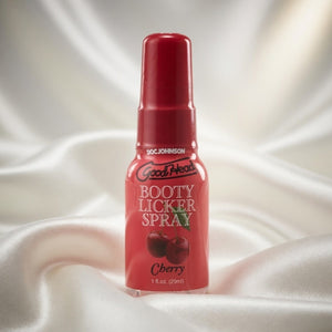 Red bottle of Good Heads Booty Licker Spray on a white fabric background