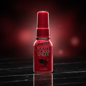 Red bottle of GoodHead Booty Licker Spray on a dark surface with a blurred red background