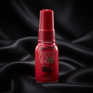 Red bottle of Good Health Booty Licker Spray on black fabric background