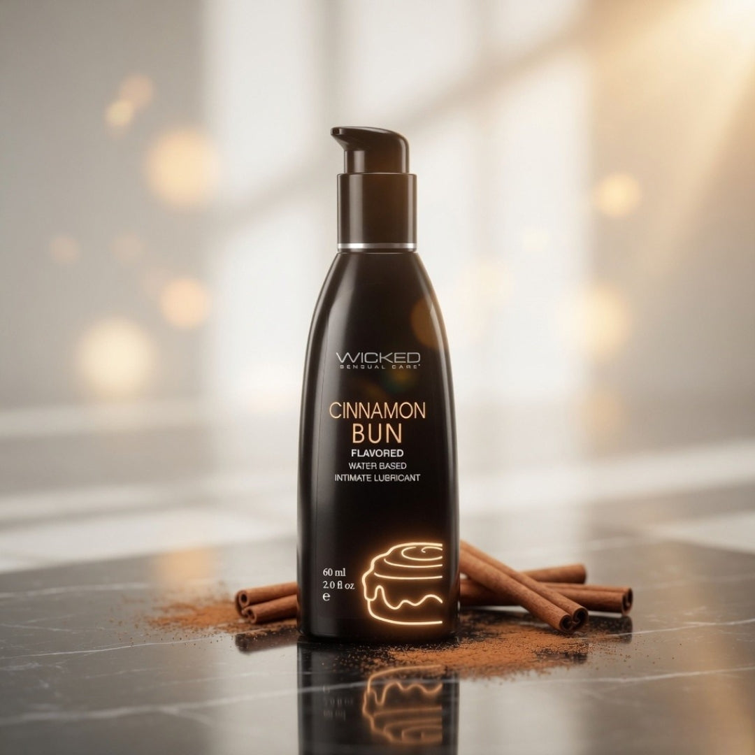 Bottle of Wicked Cinnamon Bun flavored lubricant on a reflective surface with cinnamon sticks.