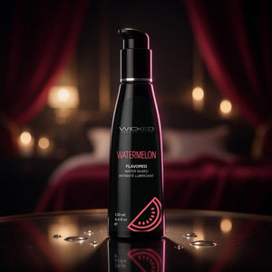 Bottle of Wicked Watermelon flavored lubricant on a reflective surface with a blurred background.