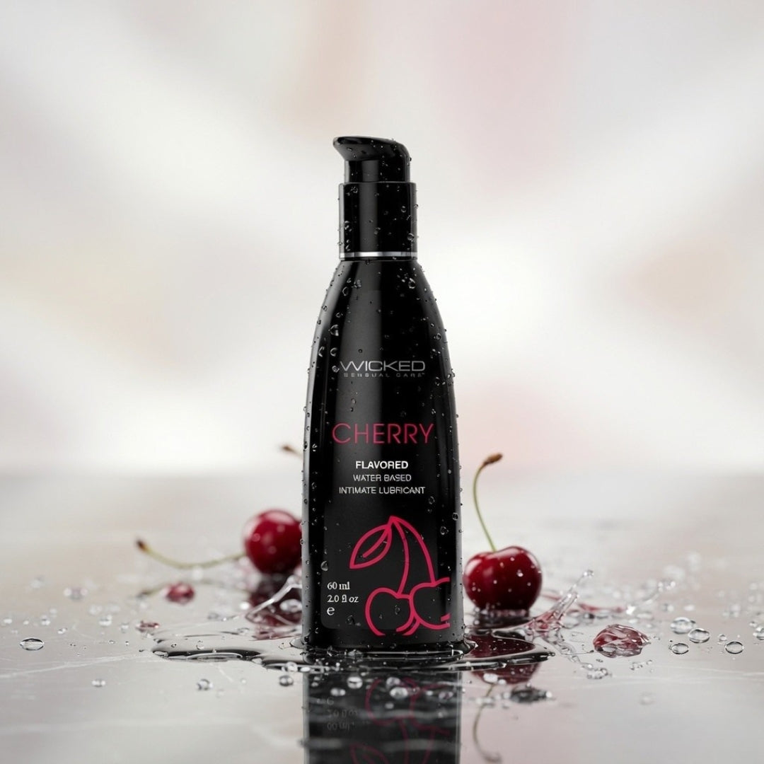 Black bottle of Wicked Cherry flavored intimate lubricant with cherries on a reflective surface.