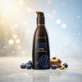 Bottle of Wicked Blueberry Muffin flavored lubricant with blueberries and a muffin on a reflective surface.