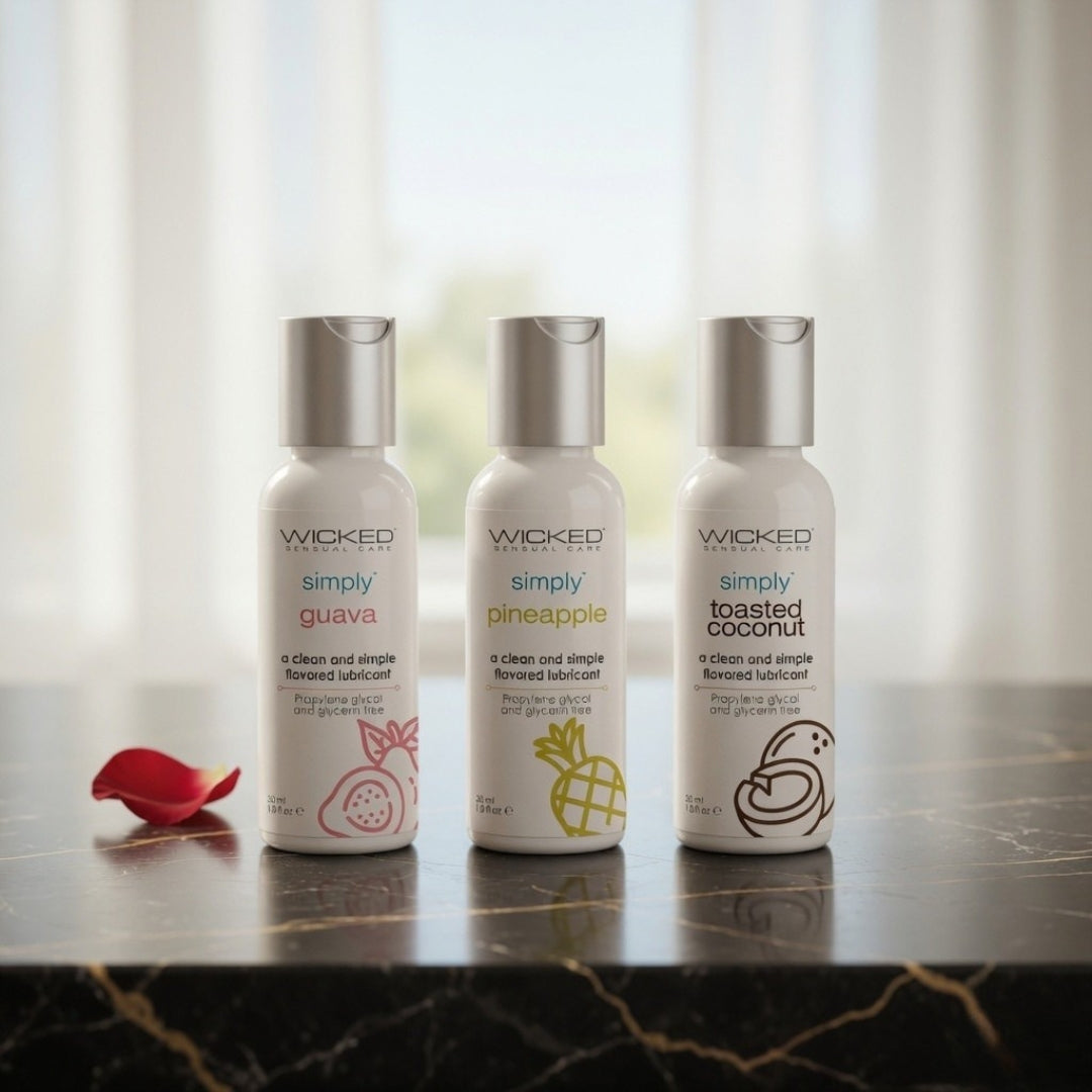 Three bottles of Wicked Sensual Care products on a marble surface with a blurred background.