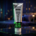 A squeeze tube of Four Seasons Personal Lubricant standing upright on a reflective glass surface against a dark, blurred background with warm bokeh lights. The tube is metallic silver with black text and a bright green 'NEW' banner near the bottom.