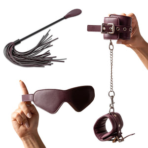Set of leather bondage accessories including a blindfold, cuffs, and whip on a white background.